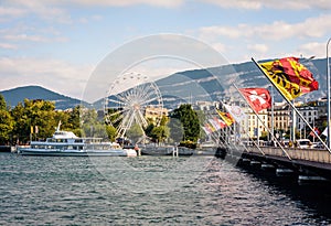 Flags on the Mont Blanc bridge, tour boat and ferris wheel in Geneva