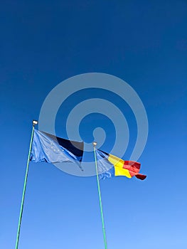 Flags of Romania and European Union against clear blue sky. Vertical. Mock up copy space
