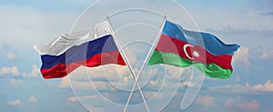 flags of Russia and Azerbaijan waving in the wind on flagpoles against sky with clouds on sunny day. Symbolizing relationship,