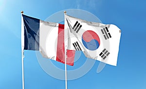 Flags of South Korea and France against the cloudy sky