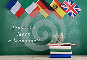 flags of Spain, France, Great Britain and other countries, blackboard with text "Want to learn a language?" and books