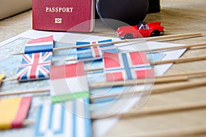 Flags on travel map, passport, retro camera, red toy car. travel destination planning concept