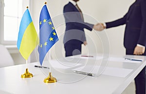 Flags of Ukraine and EU against background of representatives of countries shaking hands. photo