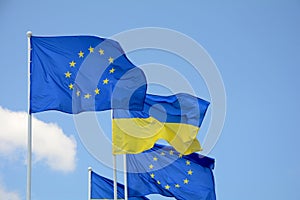 Flags of Ukraine and European Union EU against the blue sky.