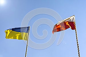 Flags of Ukraine and Poland. Two flags on the background of a beautiful blue sky and trees