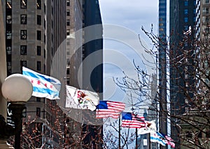 Flags of USA, Illinois and Chicago fly on a windy day along Michigan Avenue Bridge in winter.