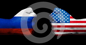 Flags of USA and Russia painted on two clenched fists facing each other on black background/Tensed relationship between USA and Ru