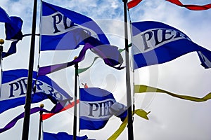 Flags wave vibrantly at Pier 39 in San Francisco under an overcast sky