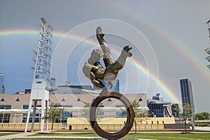 The Flair Olympic Statue in Georgia International Plaza with lush green trees and grass and a gorgeous clear blue sky