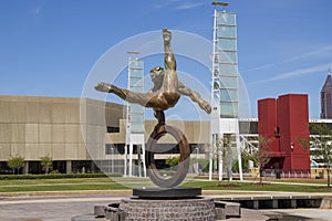 The Flair Olympic Statue in Georgia International Plaza with lush green trees and grass and a gorgeous clear blue sky