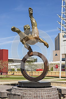 The Flair Olympic Statue in Georgia International Plaza with lush green trees and grass and a gorgeous clear blue sky