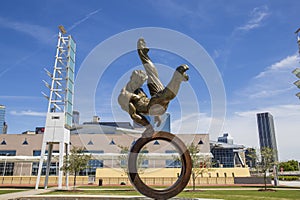 The Flair Olympic Statue in Georgia International Plaza with lush green trees and grass and a gorgeous clear blue sky