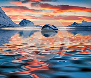 Flakstadoya island reflected in calm waters of Norwegian sea.