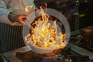 Flambe chef cooking in kitchen. Professional chef in a commercial kitchen cooking flambe style. Chef flambe cooking