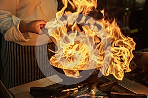 Flambe Chef Cooking in Kitchen. Professional chef in a commercial kitchen cooking flambe style. Chef Flambe Cooking