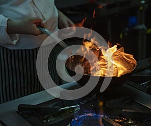 Flambe Chef Cooking in Kitchen. Professional chef in a commercial kitchen cooking flambe style. Chef Flambe Cooking