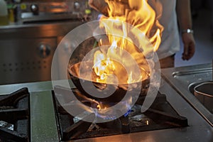 Flambe Chef Cooking in Kitchen. Professional chef in a commercial kitchen cooking flambe style. Chef Flambe Cooking