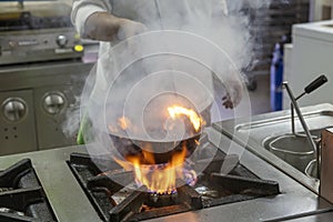 Flambe Chef Cooking in Kitchen. Professional chef in a commercial kitchen cooking flambe style. Chef Flambe Cooking