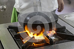 Flambe Chef Cooking in Kitchen. Professional chef in a commercial kitchen cooking flambe style. Chef Flambe Cooking