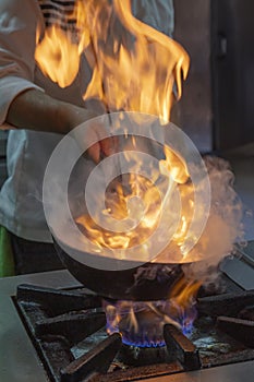 Flambe Chef Cooking in Kitchen. Professional chef in a commercial kitchen cooking flambe style. Chef Flambe Cooking