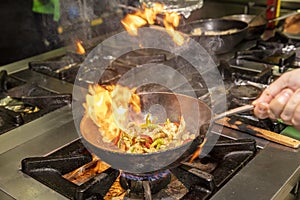 Flambe Chef Cooking in Kitchen. Professional chef in a commercial kitchen cooking flambe style. Chef Flambe Cooking