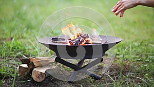 The flame of the fire burns in a metal fire bowl - warm your hands by the fire, stir the firewood with a stick. A hearth with fire