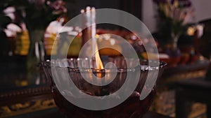 The Flame from the glass candle with a red candle in it firing on the altar