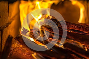 Flame incinerates firewood and transforms it ashes, close up, shallow depth of field. Blaze in a large stove. Nature