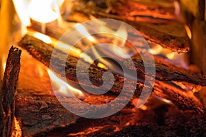 Flame incinerates firewood and transforms it ashes, close up, shallow depth of field. Blaze in a large stove. Nature