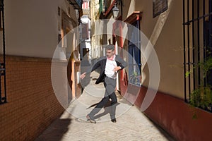 Flamenco and gipsy man, dressed in black and white shirt and red polka dots handkerchief dancing flamenco in an alley in the