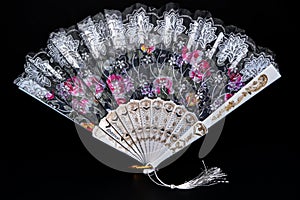 Flamenco hand fan with colorful pattern isolated on black background