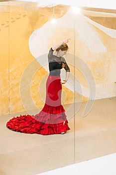 Flamenco woman dancer practicing on a studio with a tail gown