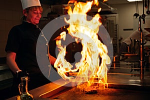 The flames in the kitchen of the restaurant. The chef prepares a steak in the restaurant`s kitchen.