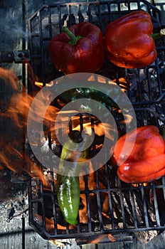 Flames smoke peppers on hibachi grill outdoors