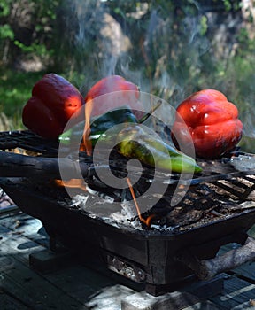 Flames smoke peppers on hibachi grill outdoors
