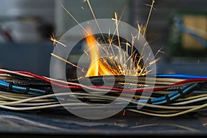 Flames, sparks, smoke between electrical cables, closeup. Short circuit in the twisted wires from the electrical devices, fire