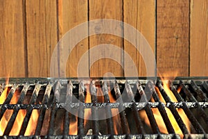 Flaming BBQ Charcoal Cast Iron Grill And Wood Background