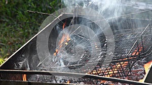 Flaming campfire and smoldering coals with gray smoke in mangal