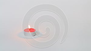Flaming red tealight candle on white