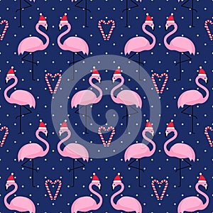 Flamingo in xmas hat with candy cane heart seamless pattern on blue polka dots background.