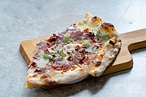 Flammkuchen Pizza Slices / Traditional Tarte Flambee with Creme Fraiche, Cream Cheese, Bacon and Red Onions on Wooden Board