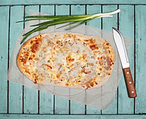 Flammkuchen or Traditional Alsatian Pie, Tart Flambe, Green Onions and Knife on Shabby Chic Vintage Wooden Background. Retro