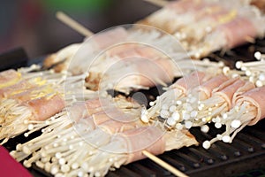 Flammulina Velutipes Mushrooms and bacon on grill.