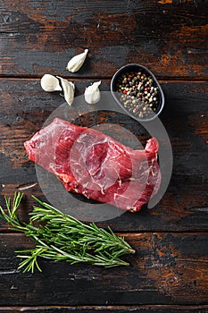 Flank, Bavette steak with seasonings, and fresh herbs raw meat, marbled beef . Dark wood rustic background. Top view photo