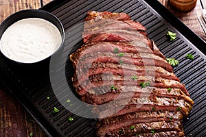 Flank steak sliced on a griddle with horseradish sauce