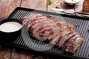 Flank steak sliced on a griddle with horseradish sauce