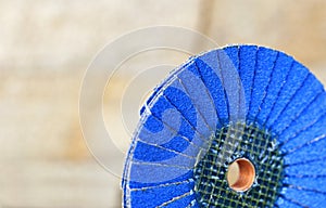 Flap grinding wheel blue on wood and metal on a light beige background in unsharp photo