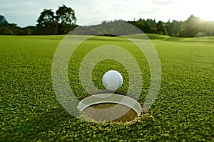 The flare lights photo of white golf ball near hole on fairway w