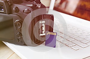 flash card in hand on camera and laptop background, memory card for SLR camera, flash drive, photo storage