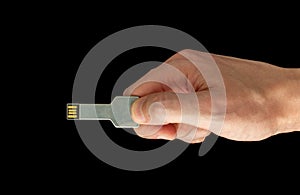 Flash Drive Disk shaped like a key in hand on isolated black background